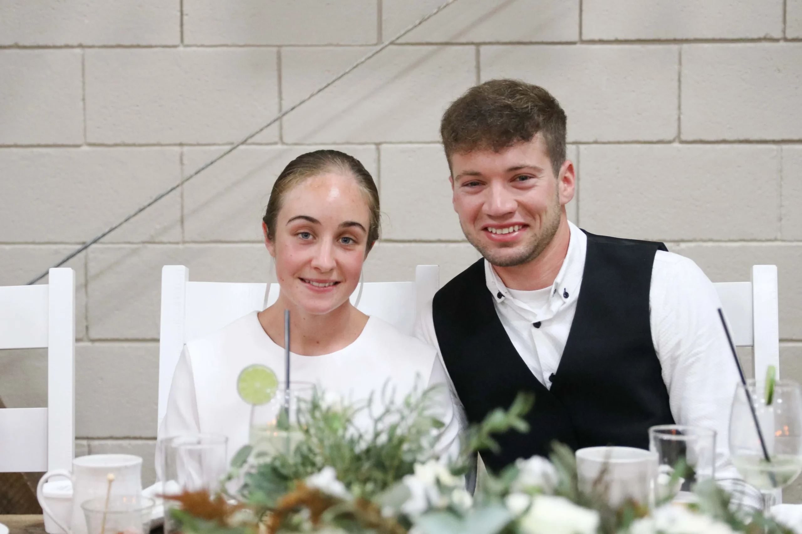 bride and groom sitting at the bridal table smiling at the camera